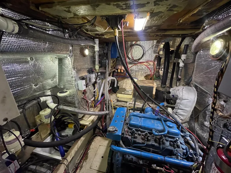 Slide: The Image of Engine room of a 1983 Islander Freeport boat with blue engine and insulated walls. - 48