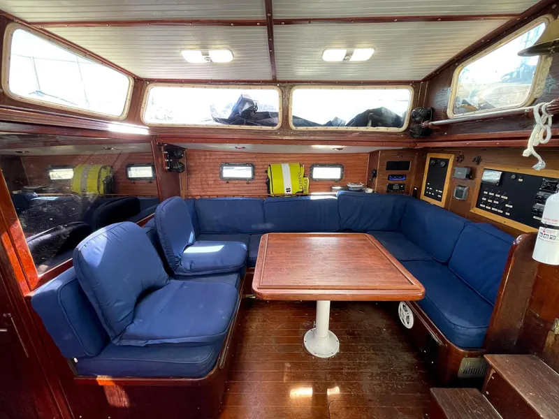 Slide: The Image of 1983 Islander Freeport yacht interior with blue cushioned seating and wooden table. - 5
