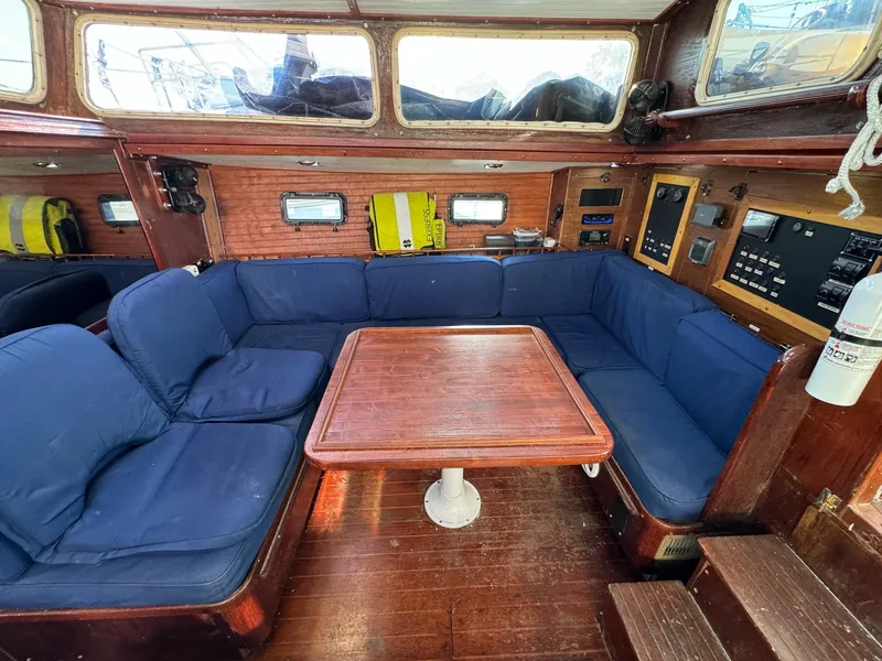 Slide: The Image of 1983 Islander Freeport yacht interior with blue cushions and wooden table. - 6