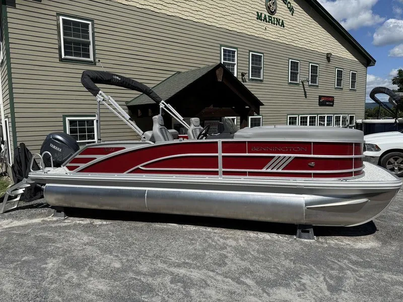 The Image of 2025 Bennington 22 MSB pontoon boat with Yamaha engine, parked outside a marina. - 0