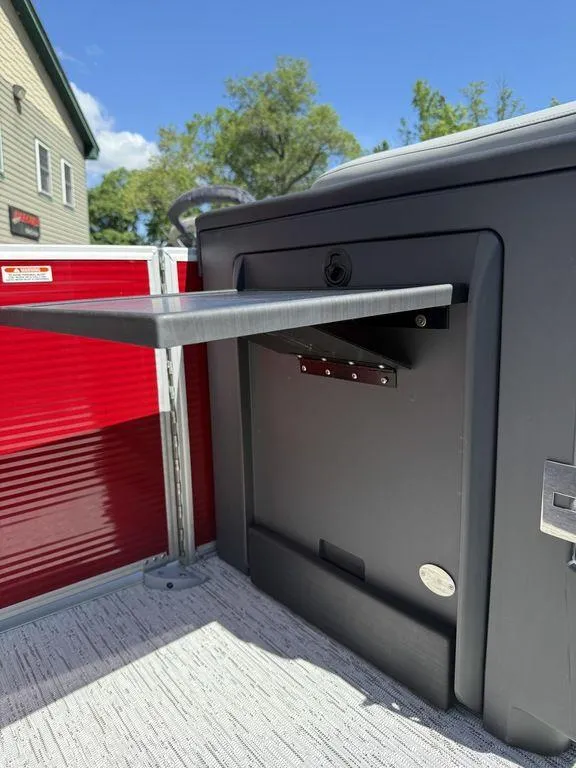 Slide: The Image of 2025 Bennington 22 MSB boat interior with fold-out table, red paneling, and sunny sky. - 18