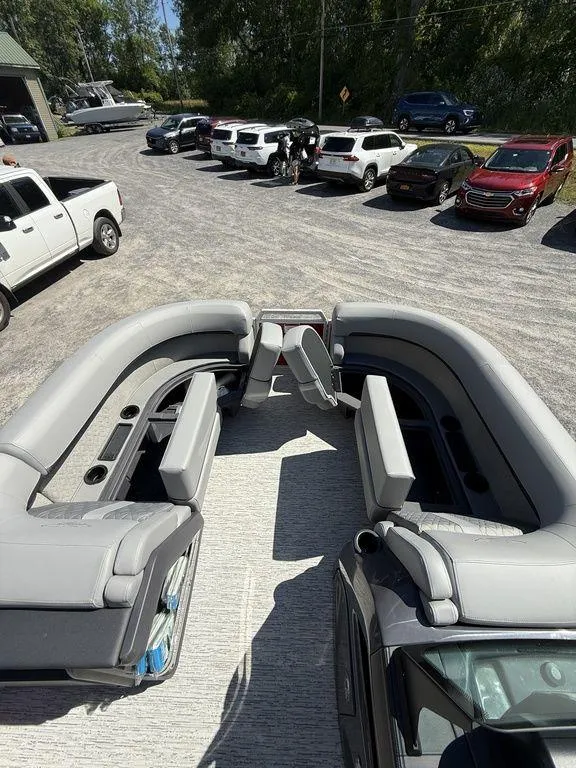 Slide: The Image of 2025 Bennington 22 MSB pontoon boat with spacious seating, parked near several cars. - 26