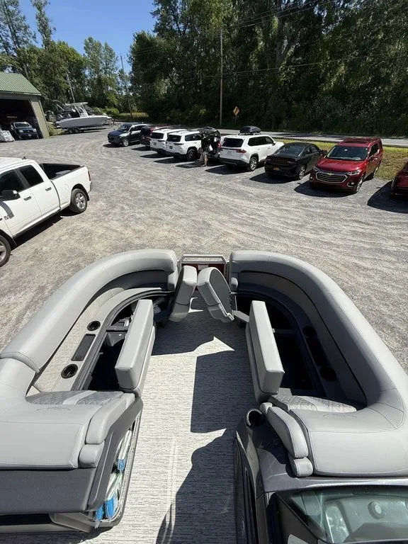 Slide: The Image of 2025 Bennington 22 MSB boat interior with gray seating, parked near vehicles. - 31