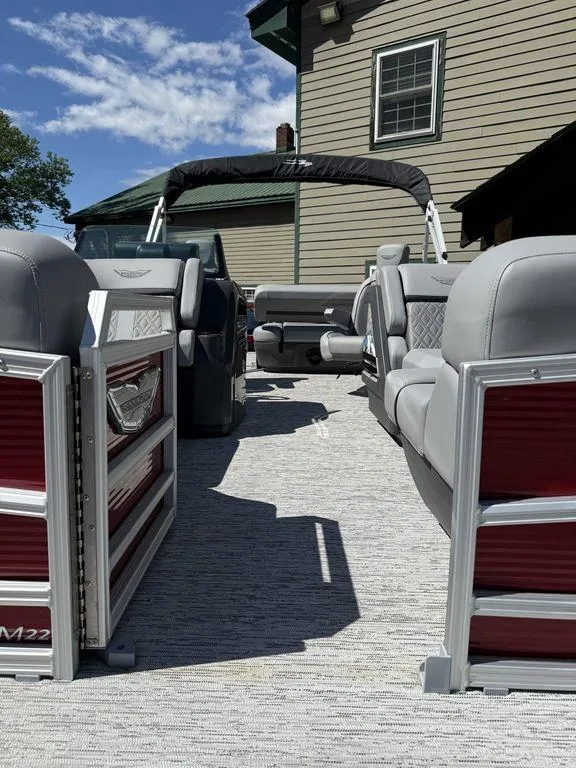 Slide: The Image of 2025 Bennington 22 MSB pontoon boat with gray seating and red accents, docked near a house. - 41
