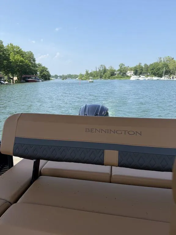 Slide: The Image of 2025 Bennington 24 MSB boat on a serene lake with lush green surroundings. - 15
