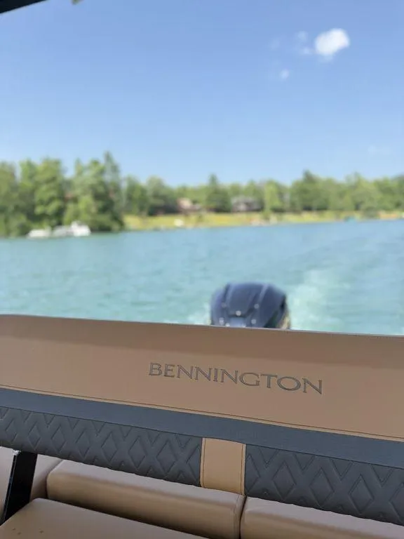 Slide: The Image of 2025 Bennington 24 MSB boat on a serene lake with clear blue skies. - 16