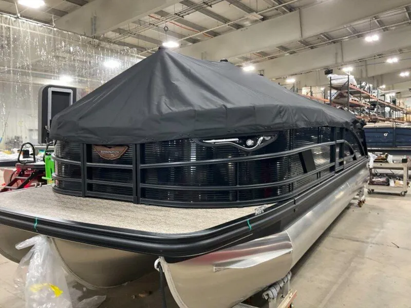 Slide: The Image of 2025 Bennington 24 MSB pontoon boat in a warehouse, covered with a black tarp. - 17