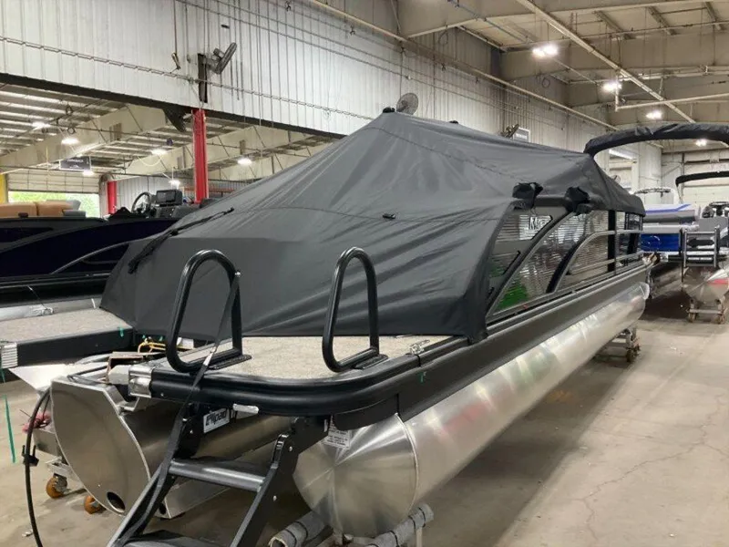 Slide: The Image of 2025 Bennington 24 MSB pontoon boat with black cover in a warehouse setting. - 22