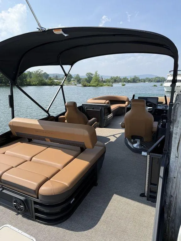 Slide: The Image of 2025 Bennington 24 MSB pontoon boat with tan seating and canopy on a scenic lake. - 3