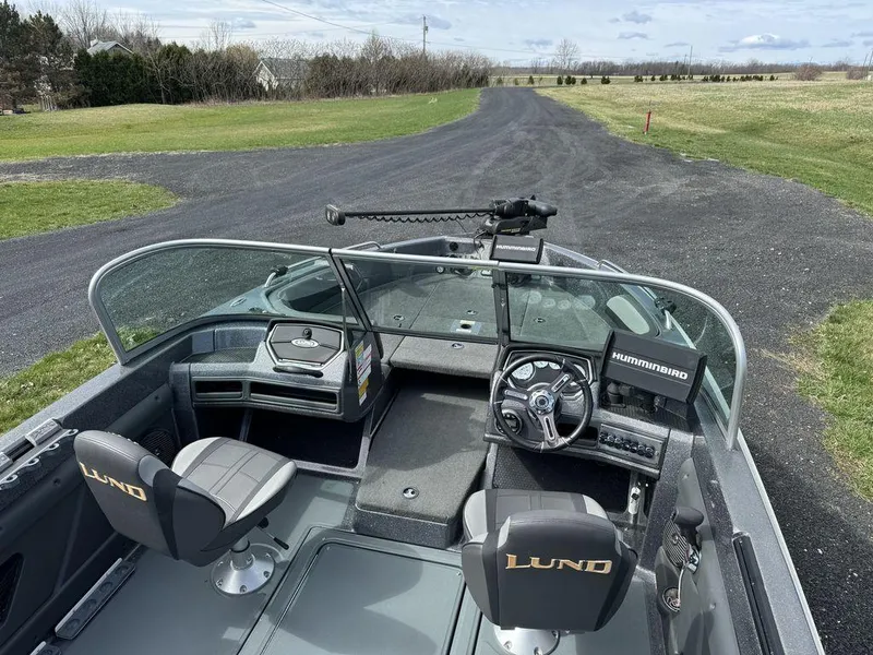 Slide: The Image of 2018 Lund 189 Tyee GL boat interior with steering wheel and seats on a paved road. - 6
