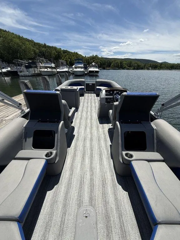 Slide: The Image of 2025 Bennington 25LSR pontoon boat interior with open storage, docked on a sunny day. - 10
