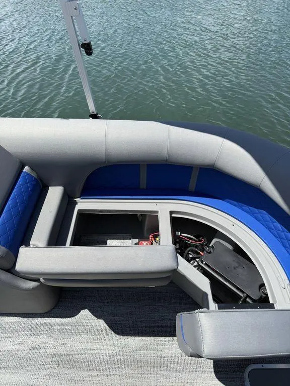 Slide: The Image of 2025 Bennington 25LSR boat interior with open storage compartment, gray and blue seating. - 12