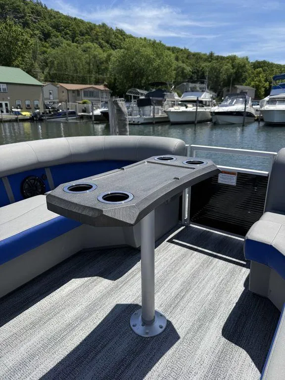 Slide: The Image of 2025 Bennington 25LSR boat interior with table and cup holders, docked at marina. - 19