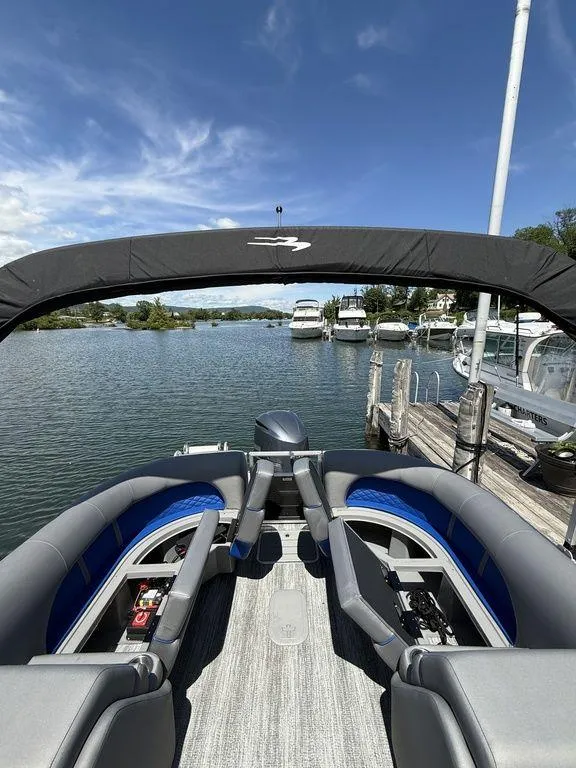 Slide: The Image of 2025 Bennington 25LSR pontoon boat docked on a sunny day, with spacious seating and scenic water view. - 2