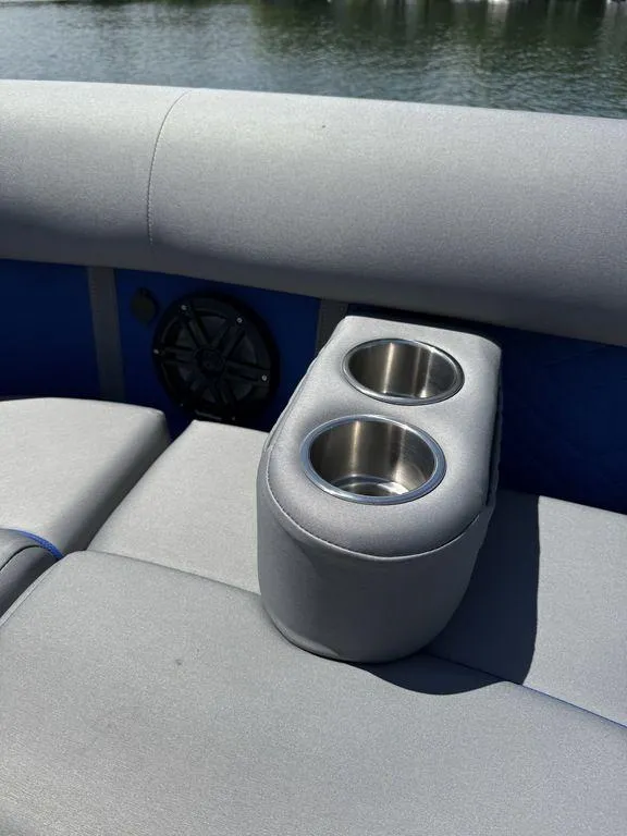 Slide: The Image of Bennington 25LSR 2025 boat interior with cup holders and speaker, on a sunny day. - 25