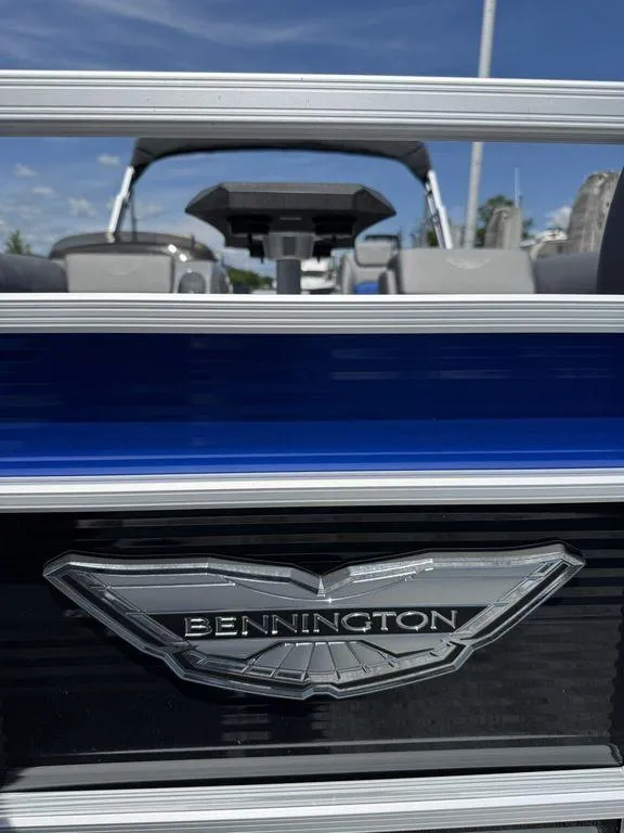 Slide: The Image of 2025 Bennington 25LSR boat with logo, blue and silver detailing, under clear sky. - 27