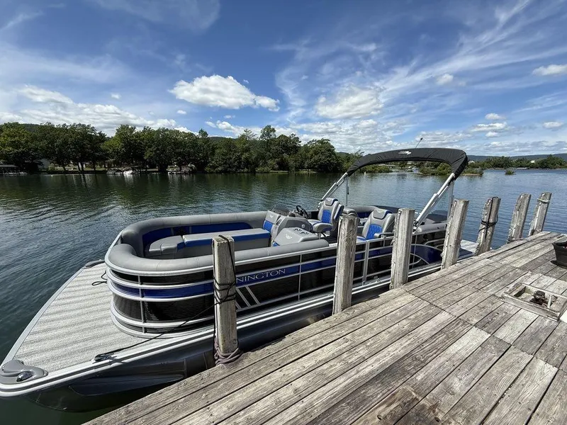 Slide: The Image of 2025 Bennington 25LSR pontoon boat docked on a serene lake under a blue sky. - 3