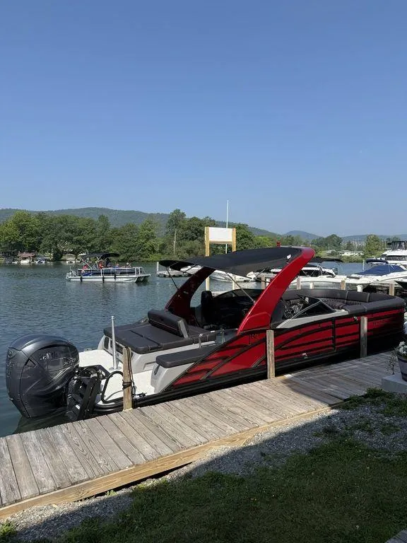Slide: The Image of 2025 Bennington 25RSBWAX1 pontoon boat docked on a scenic lake. - 0