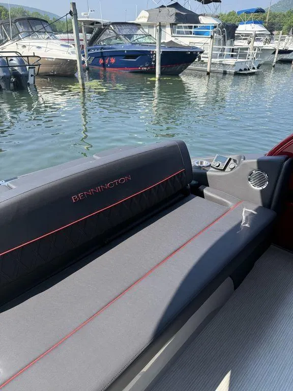 Slide: The Image of 2025 Bennington 25RSBWAX1 boat interior with sleek seating at a marina. - 10