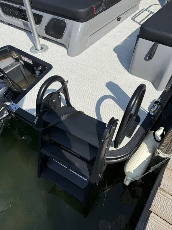 Slide: The Image of 2025 Bennington 25RSBWAX1 boat with swim ladder and deck, docked by the water. - 12