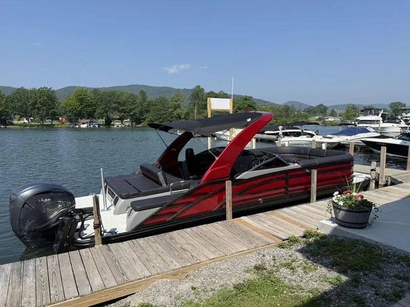 Slide: The Image of 2025 Bennington 25RSBWAX1 pontoon boat docked on a sunny lake with scenic background. - 2