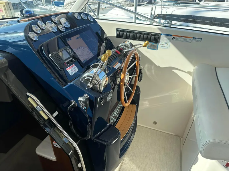 Slide: The Image of 2016 Tiara Yachts 3100 Coronet helm with gauges, controls, and wooden steering wheel. - 10