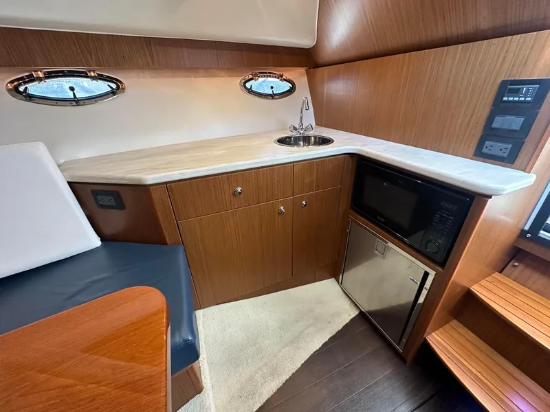 Slide: The Image of 2016 Tiara Yachts 3100 Coronet interior with kitchenette, sink, microwave, and wood finish. - 17