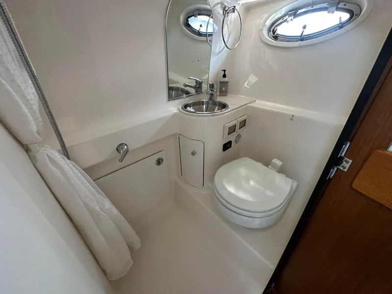Slide: The Image of 2016 Tiara Yachts 3100 Coronet bathroom with sink, toilet, and porthole window. - 19