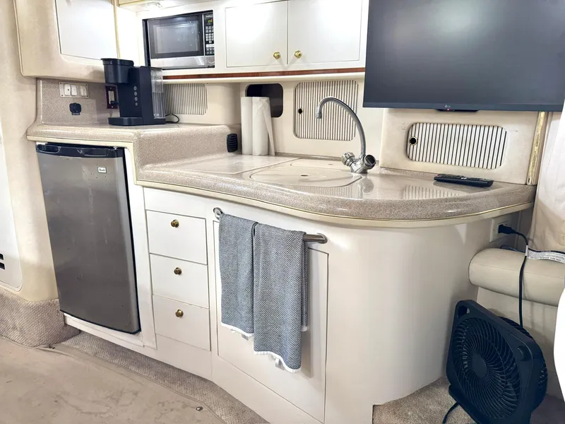 Slide: The Image of 2000 Sea Ray 340 Sundancer yacht kitchen with sink, microwave, and fridge. - 13