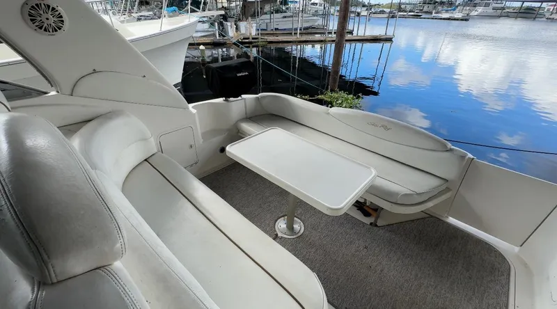 Slide: The Image of 2000 Sea Ray 340 Sundancer boat interior with seating and table, docked by the water. - 26