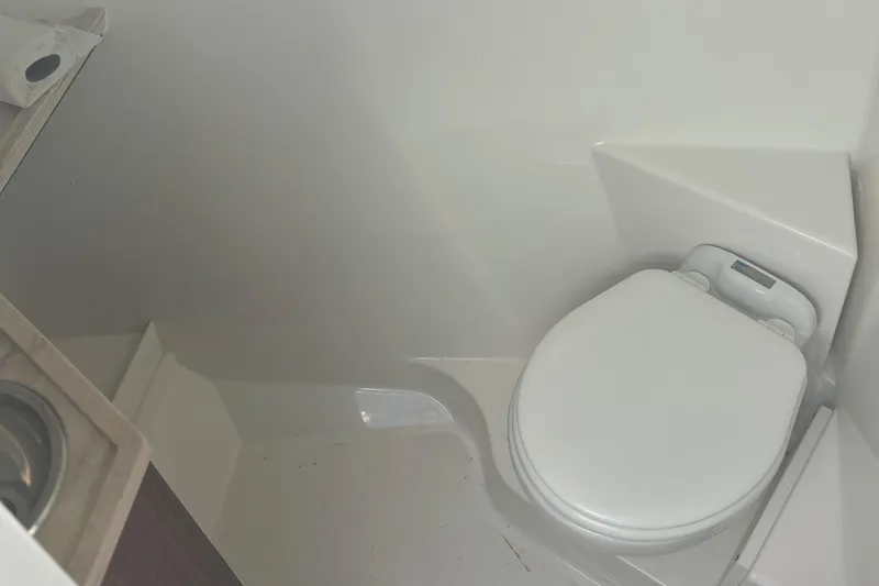 Slide: The Image of 2021 Pursuit DC 295 Dual Console boat bathroom interior with toilet and sink. - 14