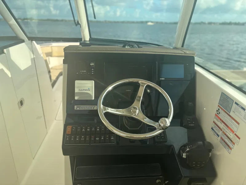 Slide: The Image of 2021 Pursuit DC 295 Dual Console boat dashboard with steering wheel and controls. - 7