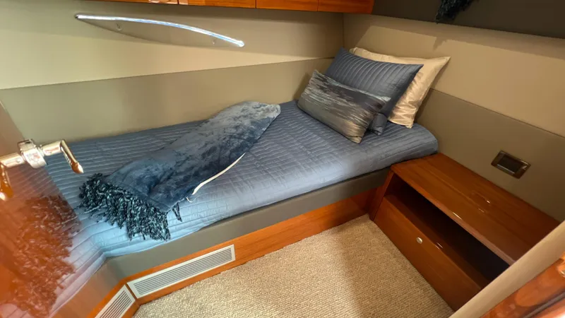 Slide: The Image of 2021 Maritimo X60 cabin with single bed, blue bedding, and wooden storage. - 42