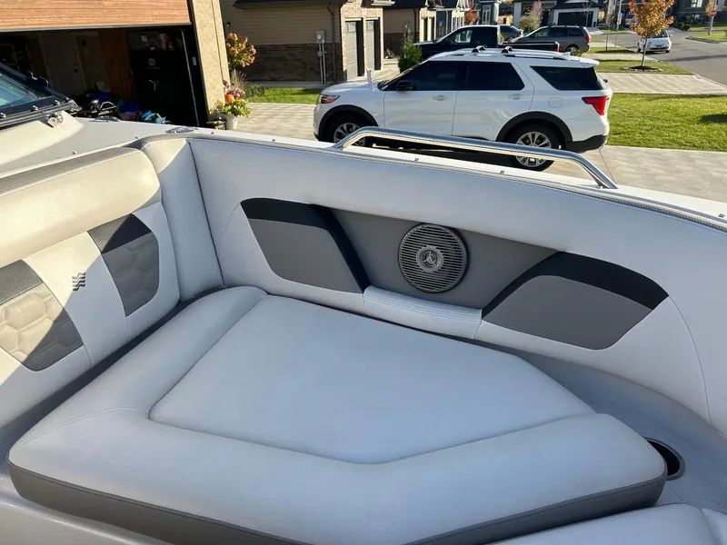 Slide: The Image of 2018 Four Winns HD220 boat interior with cushioned seating and speaker, parked in residential area. - 15