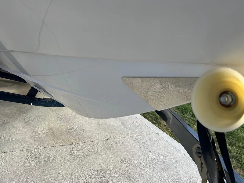 Slide: The Image of 2018 Four Winns HD220 boat hull with visible cracks and trailer roller. - 21