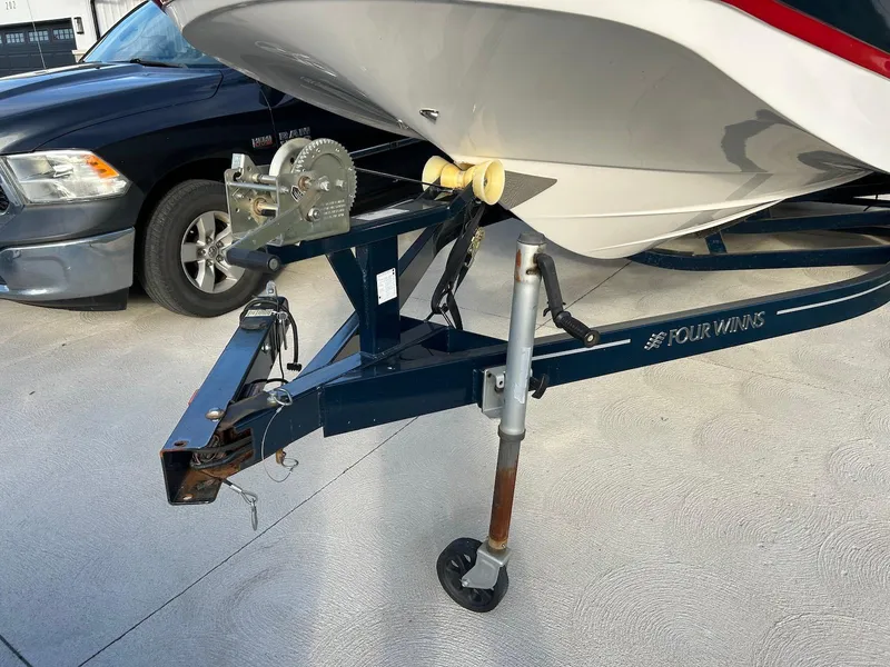 Slide: The Image of 2018 Four Winns HD220 boat on trailer, parked beside a black vehicle. - 22