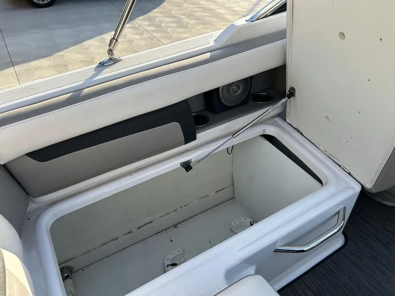 Slide: The Image of 2018 Four Winns HD220 boat interior storage compartment with open lid and cup holders. - 28