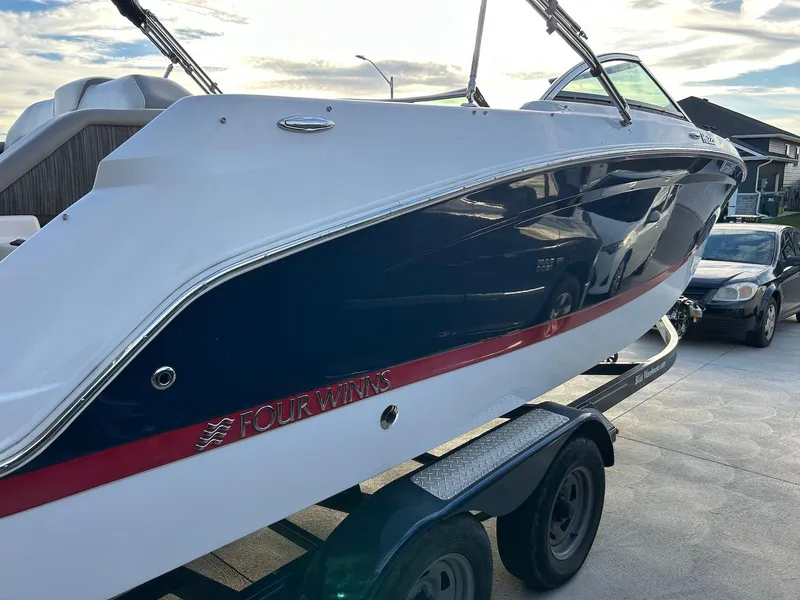 Slide: The Image of 2018 Four Winns HD220 boat on trailer, sleek design with blue and white exterior. - 3