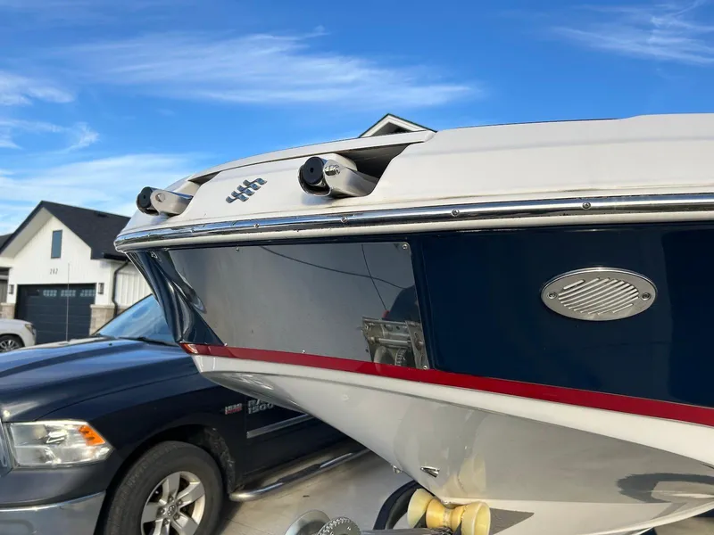Slide: The Image of 2018 Four Winns HD220 boat bow with sleek design, parked near a house and vehicle. - 4