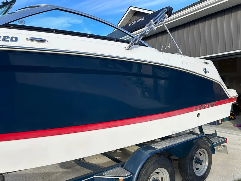 Slide: The Image of 2018 Four Winns HD220 boat on trailer, blue and white with red stripe. - 5