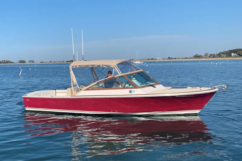 The Image of 2013 Hunt Yachts Harrier 25 boat on calm water, red hull, beige canopy. - 0