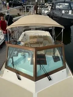 Slide: The Image of 2013 Hunt Yachts Harrier 25 near a serene shoreline with lush greenery. - 7