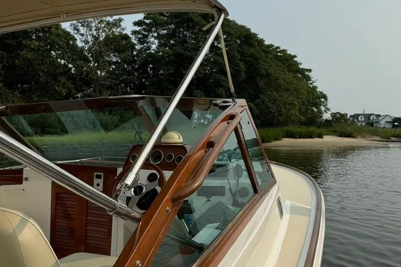 Slide: The Image of 2013 Hunt Yachts Harrier 25 interior with beige seating and wooden accents on a calm river. - 6
