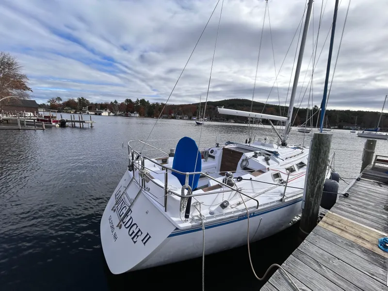 Slide: The Image of 1983 Hunter 34 sailboat docked at a marina under cloudy skies. - 1