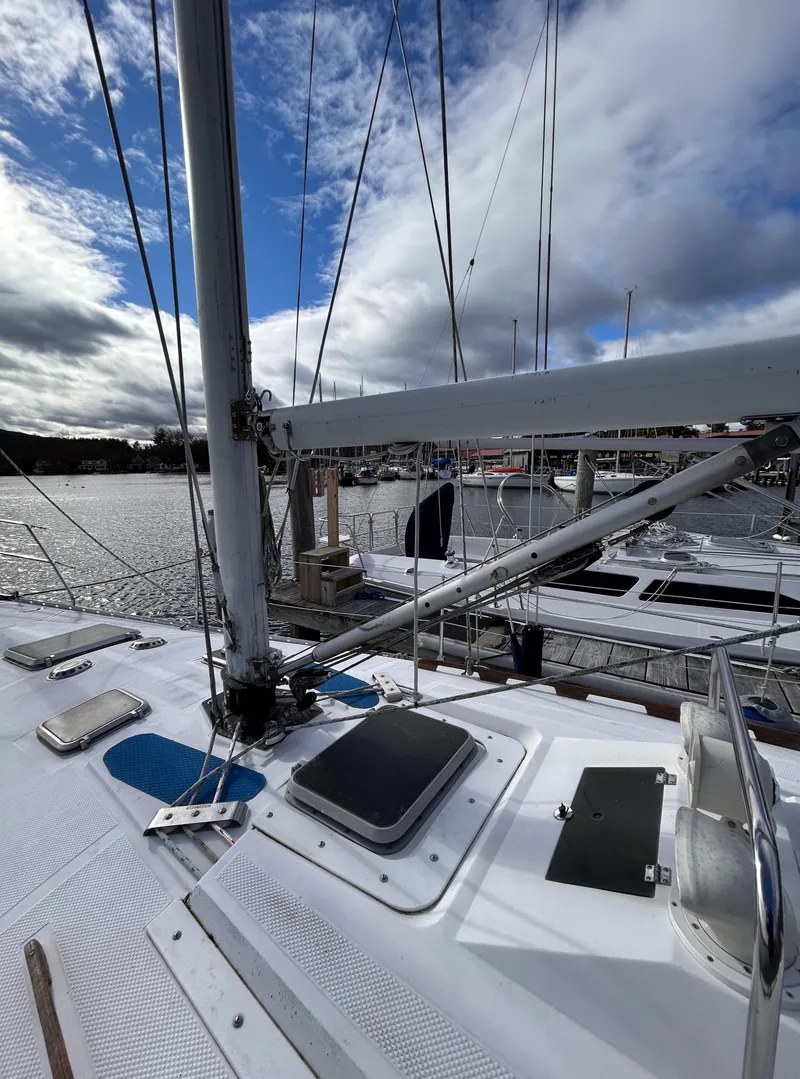 Slide: The Image of 1983 Hunter 34 sailboat docked, featuring deck and mast under a partly cloudy sky. - 17