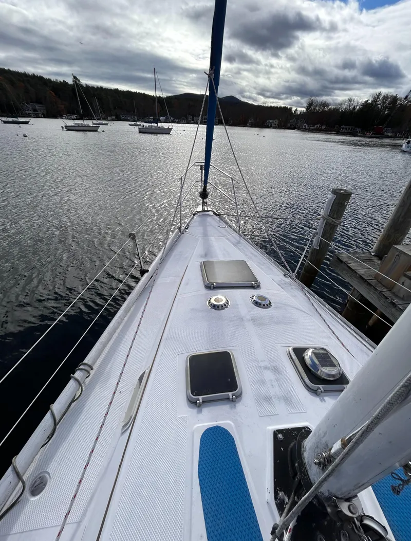 Slide: The Image of 1983 Hunter 34 sailboat on calm water, cloudy sky, docked in a serene marina. - 21