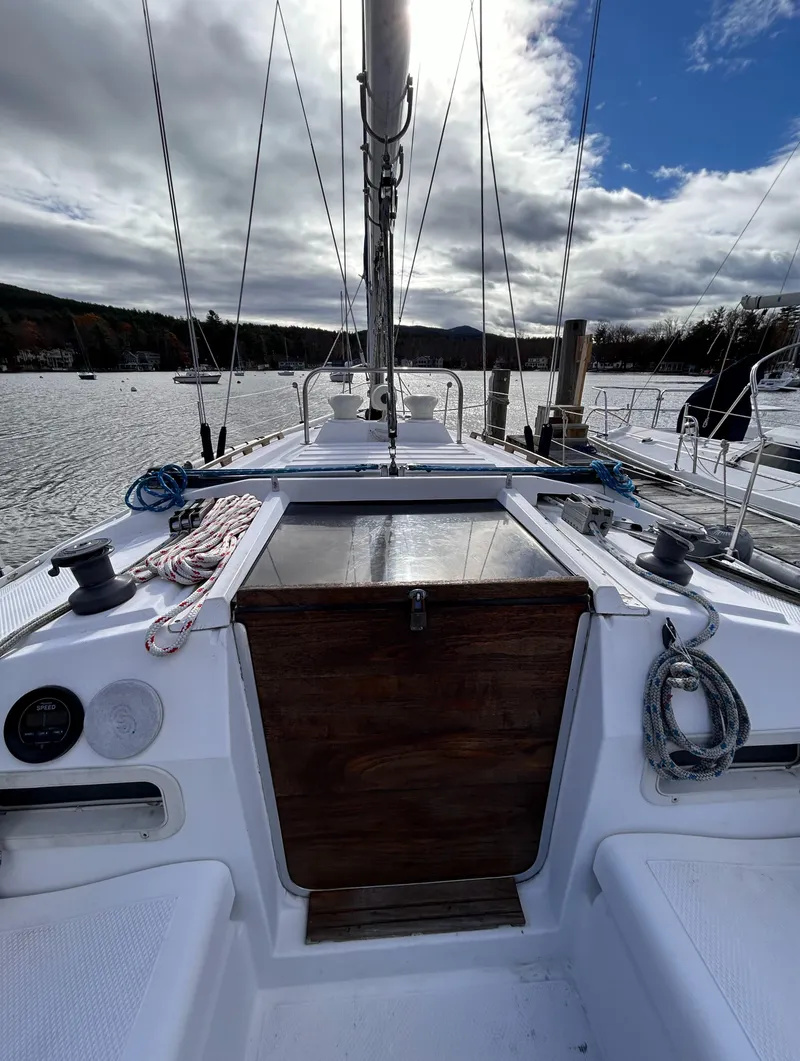 Slide: The Image of 1983 Hunter 34 sailboat cockpit with ropes and winches, moored on a calm lake under cloudy skies. - 26
