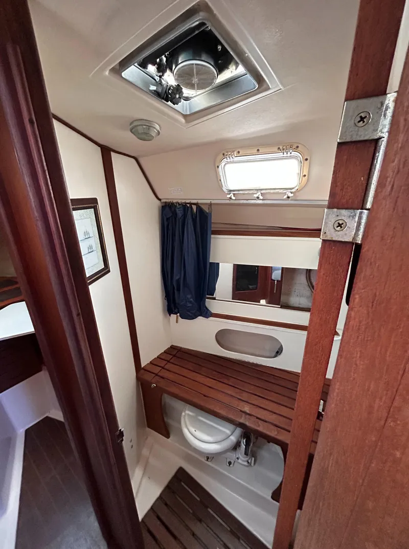 Slide: The Image of 1983 Hunter 34 sailboat bathroom with wooden accents and porthole window. - 47