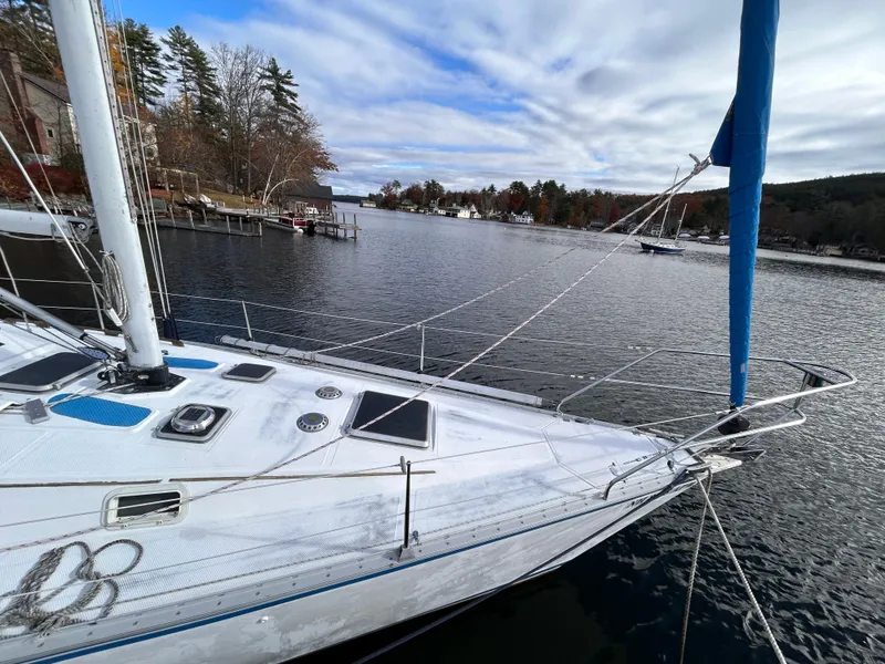 Slide: The Image of 1983 Hunter 34 sailboat docked on a serene lake with a scenic backdrop. - 6