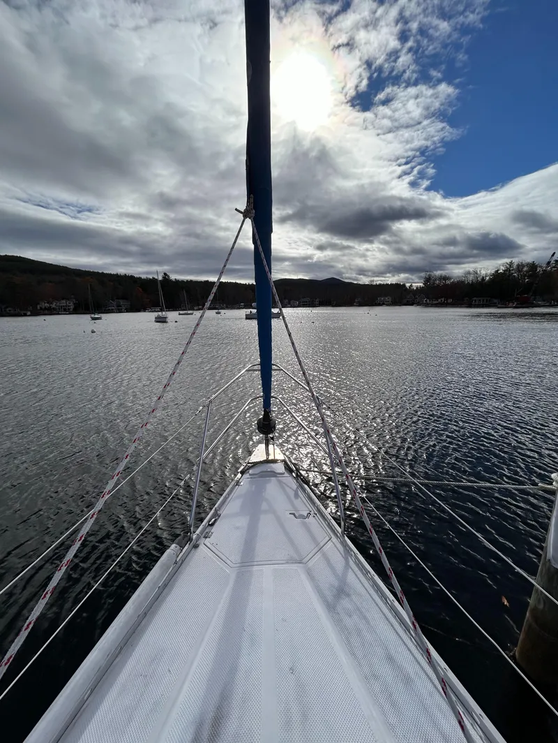 Slide: The Image of 1983 Hunter 34 sailboat on a serene lake under a partly cloudy sky. - 7